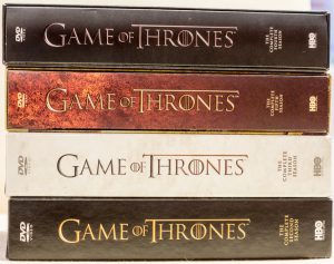 London, UK - June 14, 2016: A studio shot on a white background of the fantasy drama series Game of Thrones DVD boxset featuring four of the first five seasons. All the books were written by George RR Martin while the series was created by David Benioff and DB Weiss and produced by HBO.